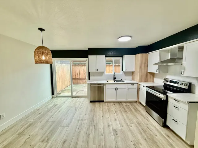 a kitchen with stainless steel appliances granite countertop a sink a stove top oven a counter space and cabinets