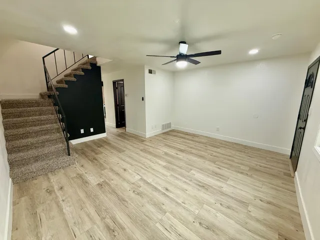 an empty room with wooden floor closet and windows