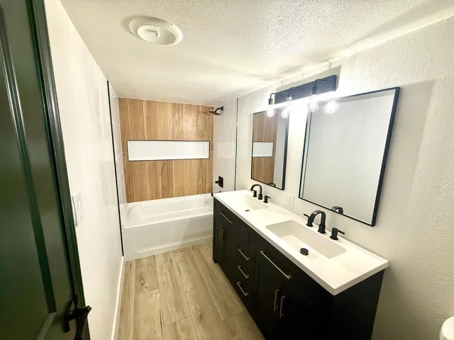a bathroom with a double vanity sink a mirror and a bathtub
