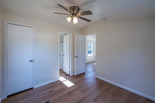 an empty room with wooden floor and a ceiling fan