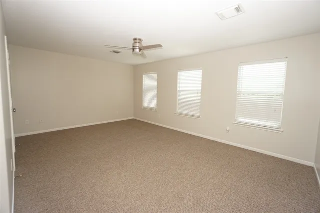 an empty room with chandelier fan and windows
