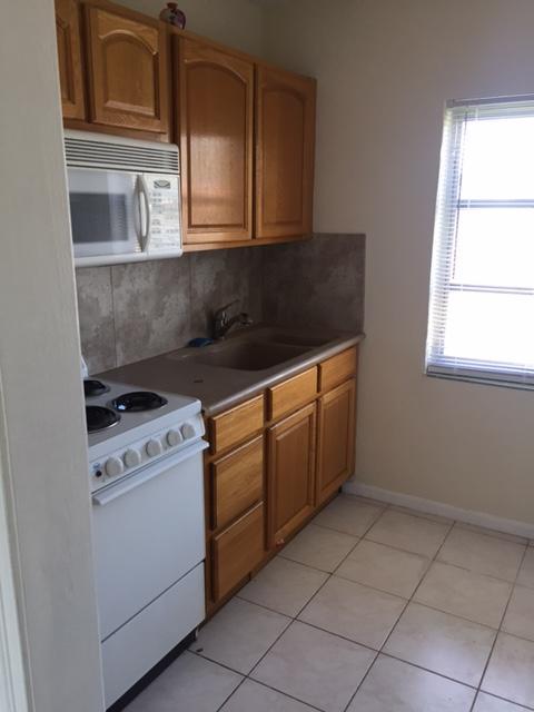 101 South Golfview Road, Unit 16 Lake Worth Beach, FL 33460 - Photo 12 of 16 a kitchen with granite countertop white cabinets and white appliances