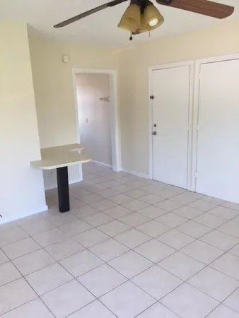 a view of an empty room and chandelier fan