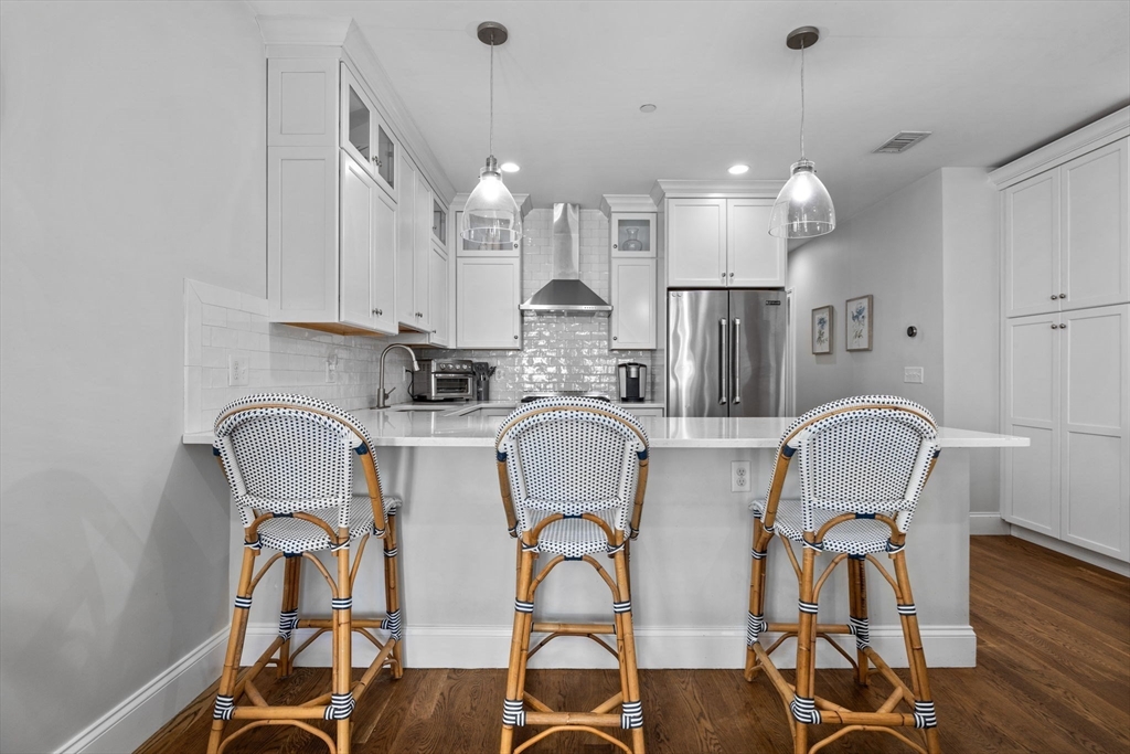 25 Mercer Street, Unit PH5 Boston, MA 02127 - Photo 9 of 22 a kitchen with stainless steel appliances granite countertop a dining table chairs and white cabinets