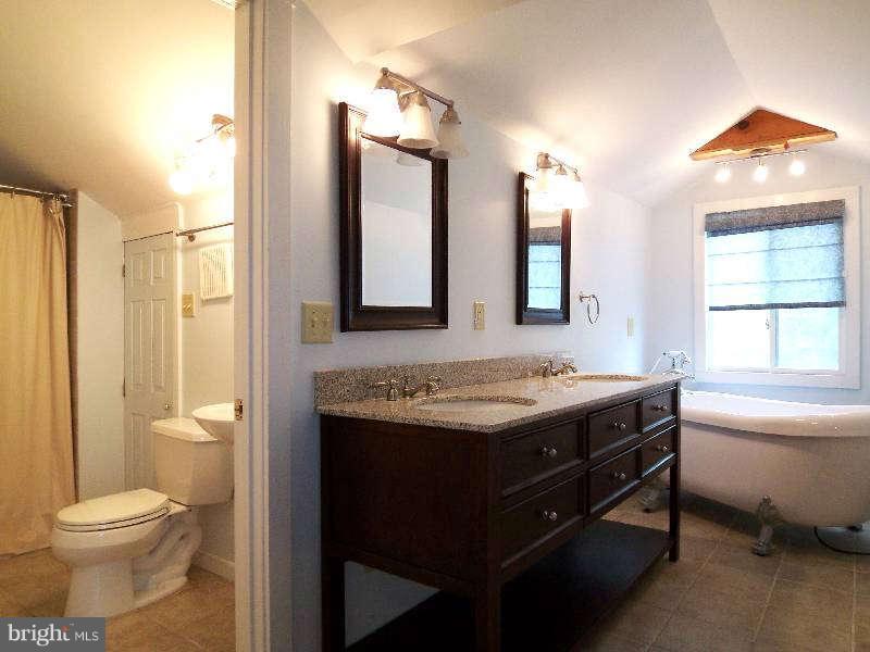 2 Warren Street Berkeley Springs, WV 25411 - Photo 24 of 30 a bathroom with a granite countertop toilet a sink a mirror and a window