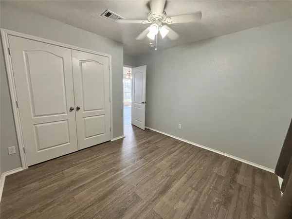 an empty room with wooden floor fan and windows