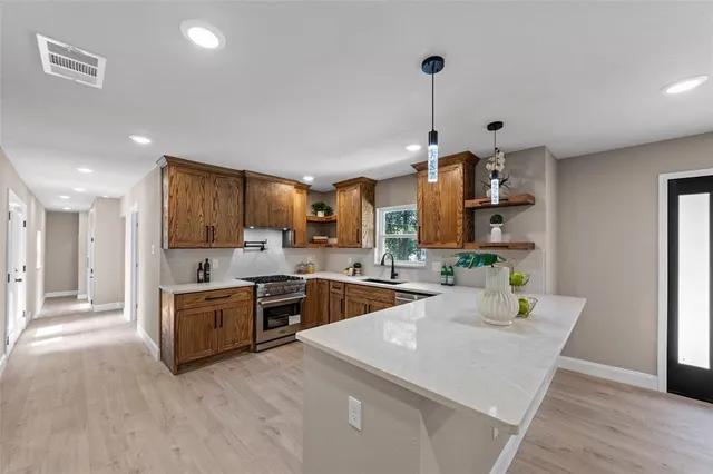 a kitchen with stainless steel appliances granite countertop a stove refrigerator and a sink