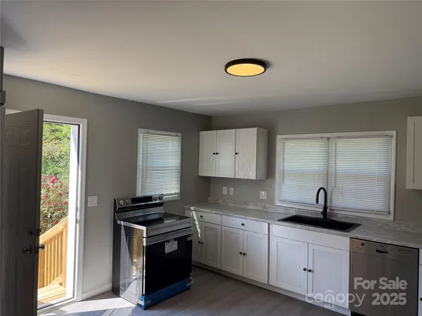 a kitchen with granite countertop a sink a stove and cabinets