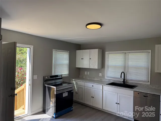 a kitchen with granite countertop a sink a stove and cabinets