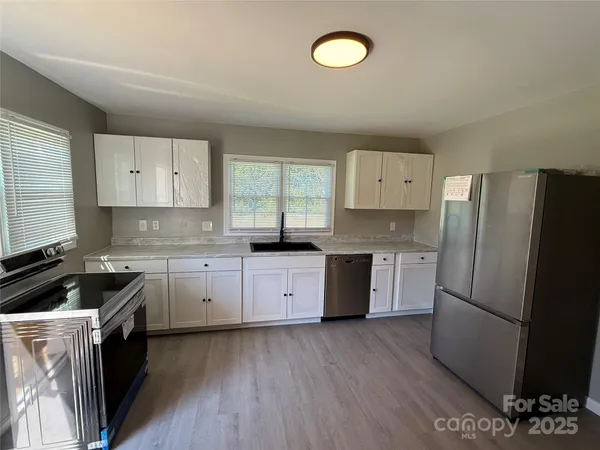 a kitchen with granite countertop a refrigerator stove top oven and sink