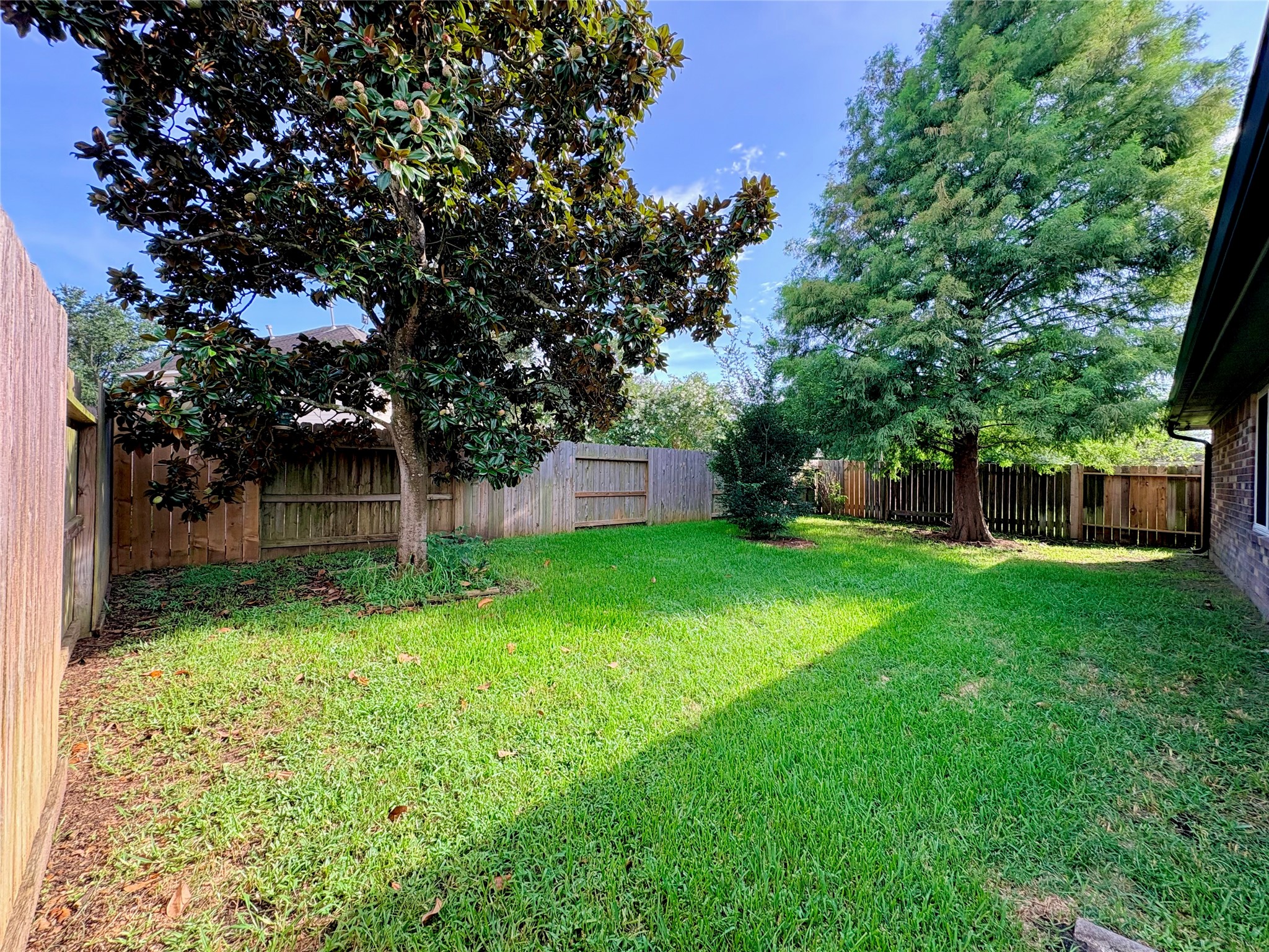 15410 Redbud Berry Way Cypress, TX 77433 - Photo 47 of 49 This photo showcases a spacious, fenced backyard featuring well-maintained grass and mature trees, offering privacy and a serene outdoor space.