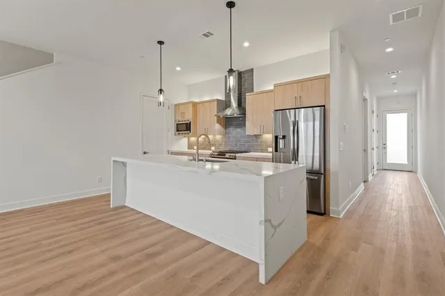 a kitchen with kitchen island a refrigerator and a stove top oven