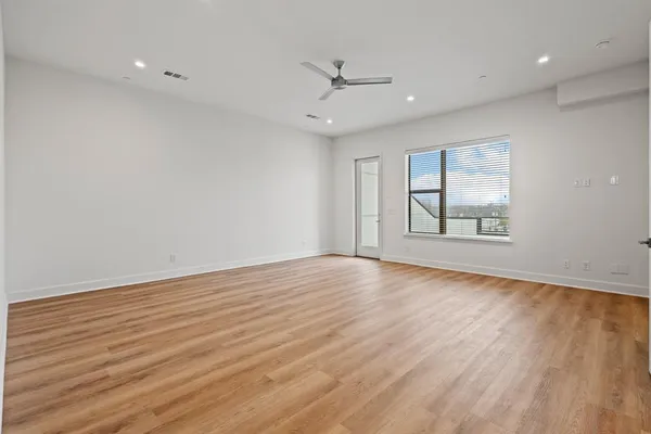 an empty room with wooden floor ceiling fan and windows