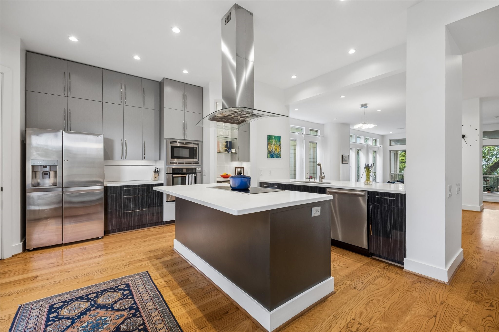 1518 West Clay Street Houston, TX 77019 - Photo 15 of 36 Kitchen showing island with stainless steel appliance cooktop, overhead exhaust, refrigerator, oven and microwave, breakfast bar w/ dishwasher plus cabinetry.
