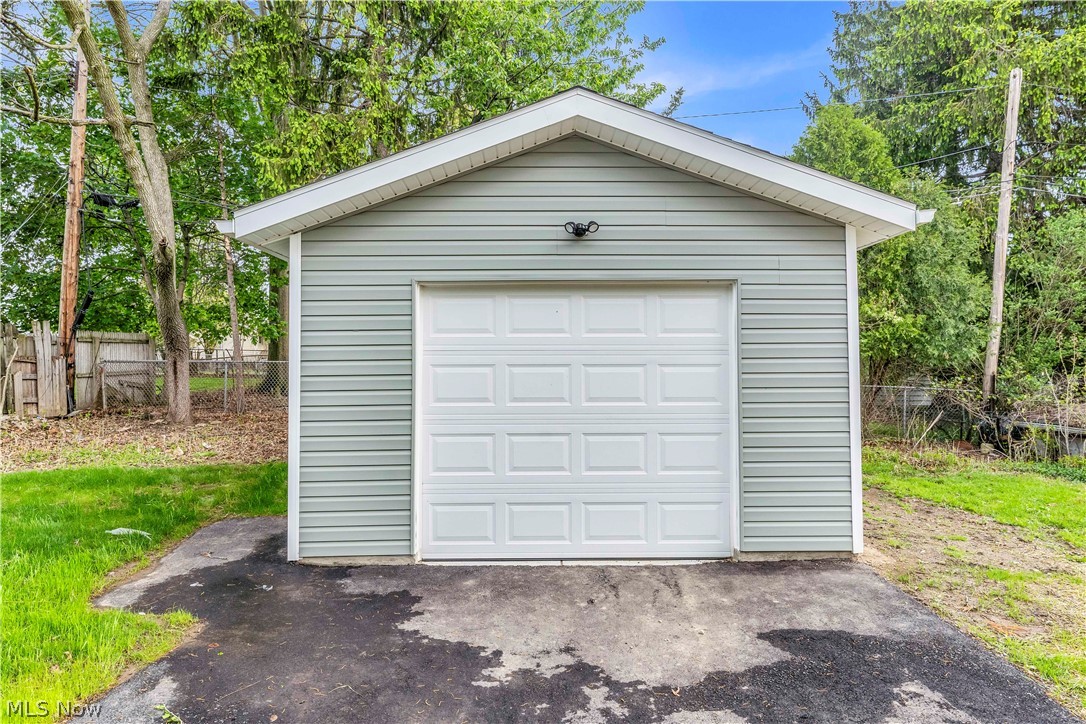 18155 Libby Road Maple Heights, OH 44137 - Photo 31 of 32 Detached single-car garage featuring light gray horizontal siding, a white paneled garage door, and a white soffit and fascia