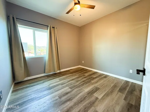 a view of an empty room with wooden floor and a window