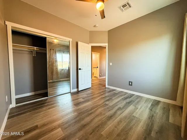 an empty room with wooden floor cabinet and windows