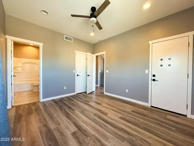 a view of empty room with wooden floor and fan