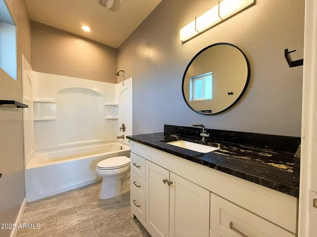 a bathroom with a granite countertop toilet a sink and a mirror