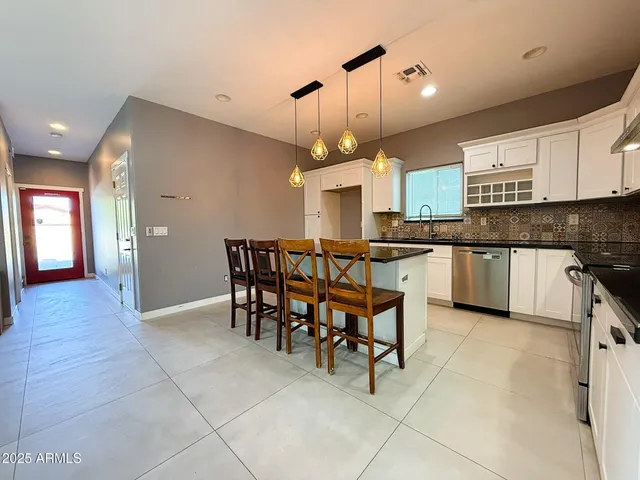 a kitchen with stainless steel appliances a dining table chairs stove and cabinets