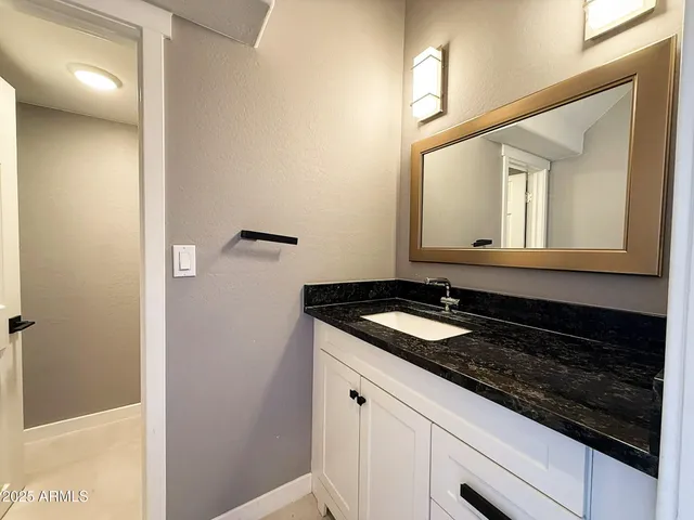 a bathroom with a granite countertop sink and a mirror