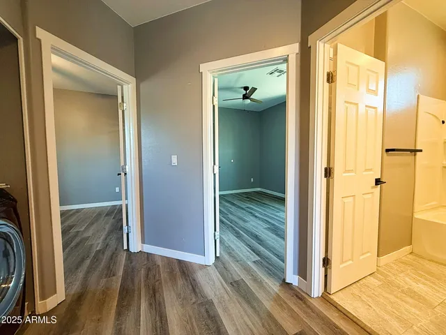a view of a hallway with wooden floor and a bathroom