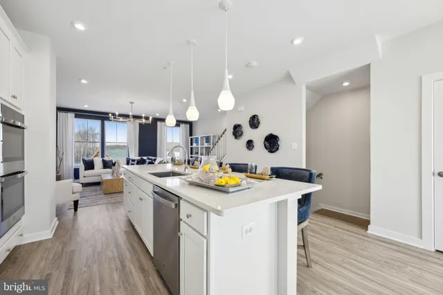 a kitchen with a sink a stove and chairs with wooden floor