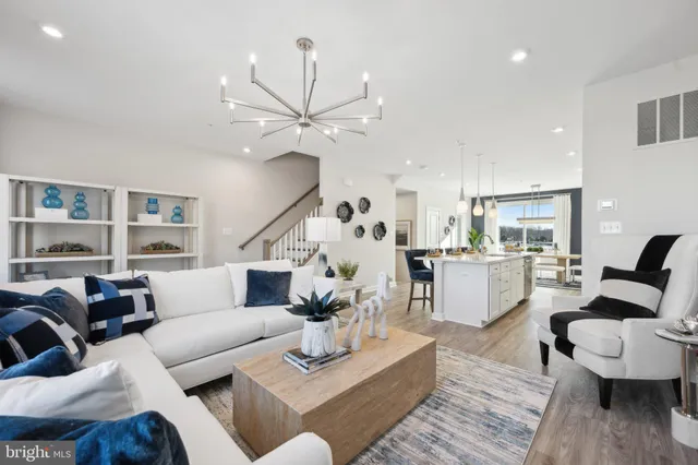 a living room with furniture kitchen view and a wooden floor