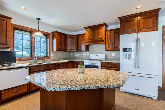 a kitchen with granite countertop a sink a counter top space cabinets and stainless steel appliances