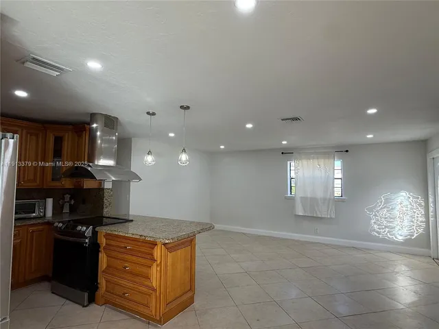 a kitchen with stainless steel appliances kitchen island granite countertop a stove a refrigerator and a sink