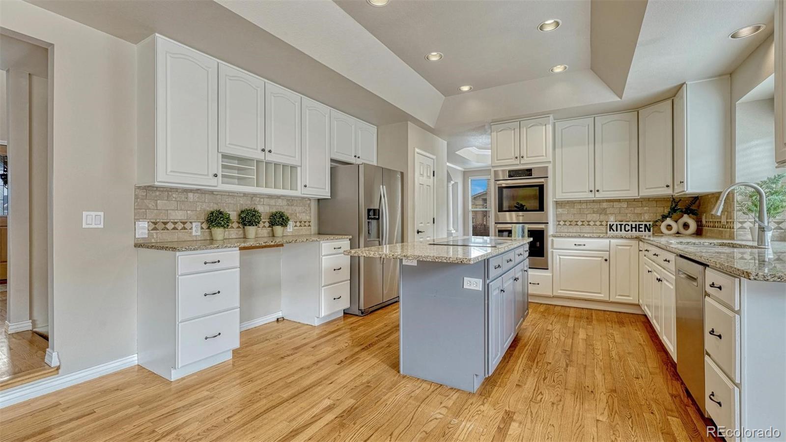 15211 Ridgefield Lane Colorado Springs, CO 80921 - Photo 11 of 47 a kitchen with stainless steel appliances granite countertop a stove top oven a sink dishwasher and a refrigerator with wooden floor