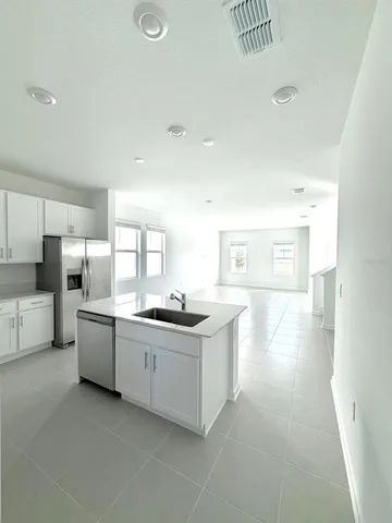 a kitchen with stainless steel appliances a stove a sink a refrigerator and white cabinets