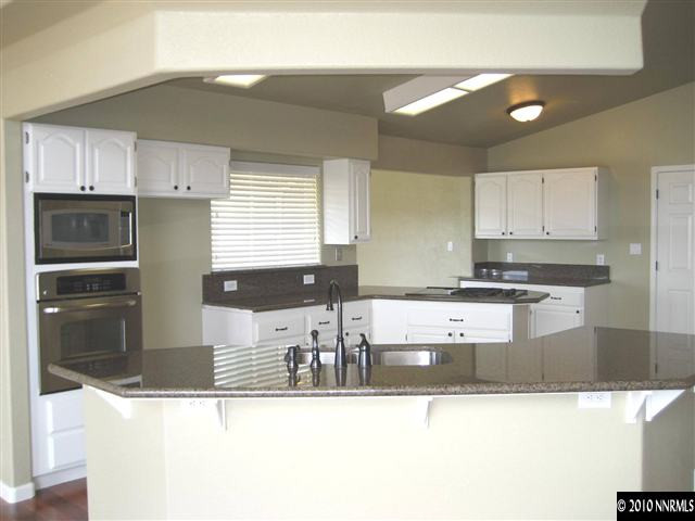 690 Tarn Way Reno, NV 89503 - Photo 6 of 13 a kitchen with stainless steel appliances granite countertop a refrigerator a stove and a sink with wooden cabinets