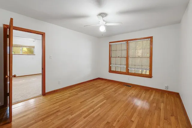 a view of an empty room with wooden floor and a window