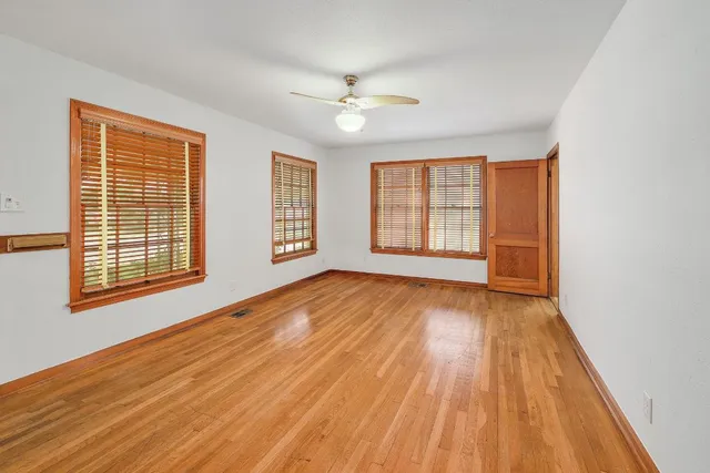 an empty room with wooden floor and windows