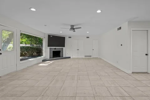 an empty room with windows and fireplace