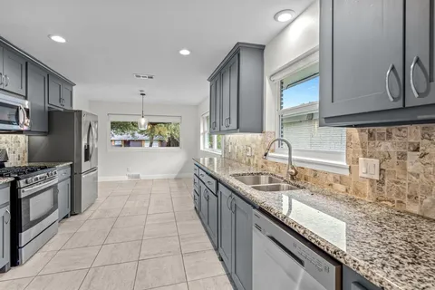 a large kitchen with granite countertop a sink and cabinets