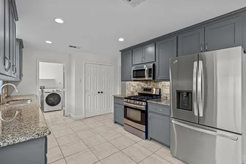 a kitchen with stainless steel appliances granite countertop a refrigerator stove and sink