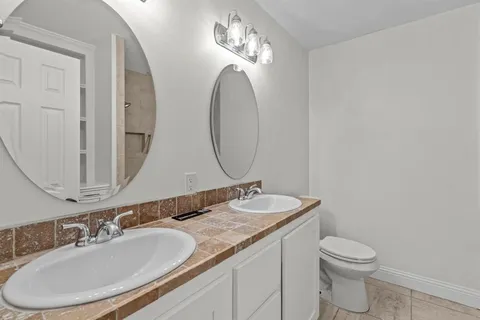 a bathroom with a granite countertop toilet a sink and a mirror
