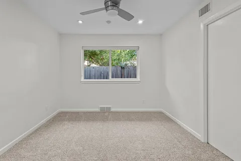 an empty room with a window and a ceiling fan