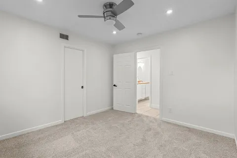 an empty room with a ceiling fan and carpet