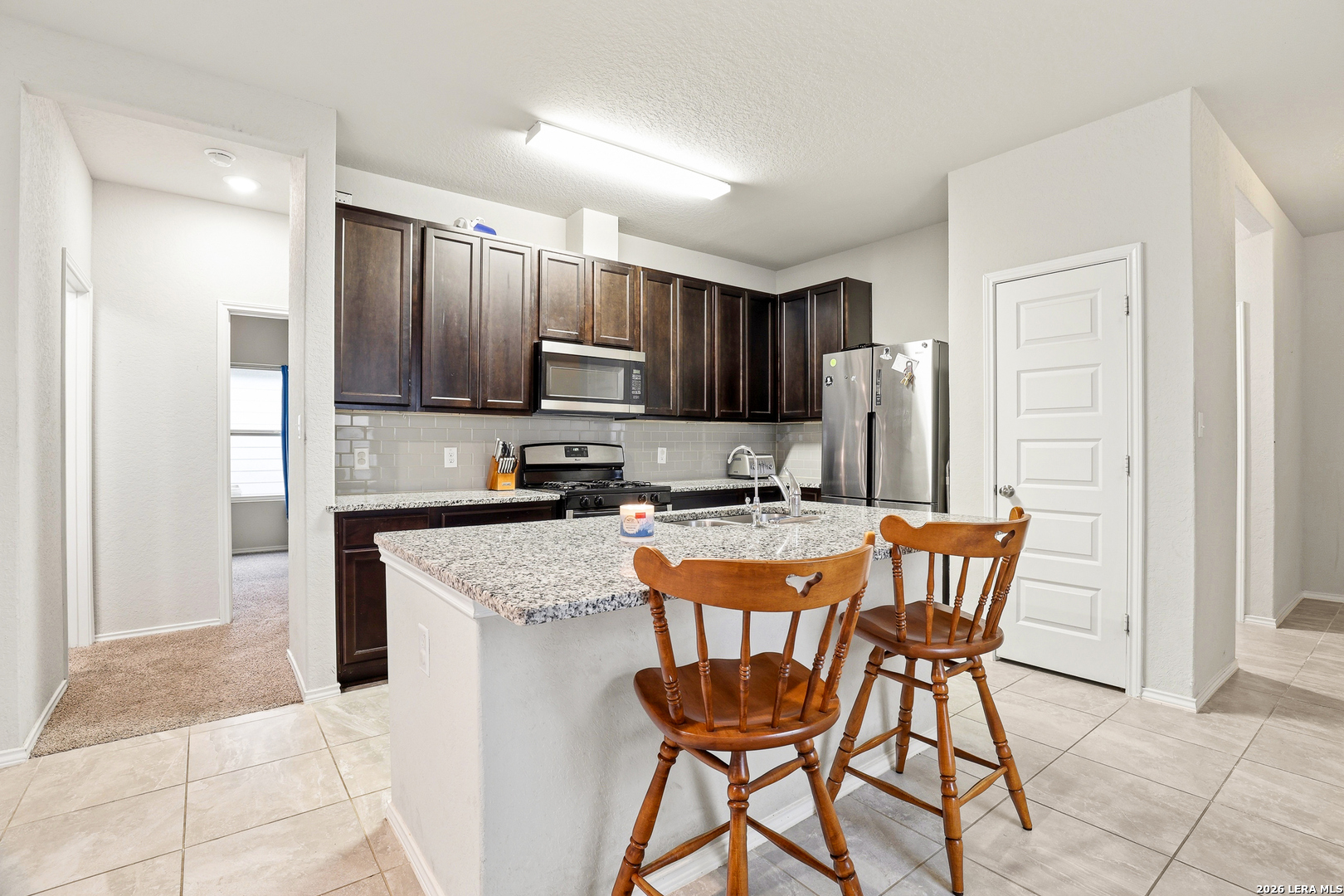 5314 Riley Way St. Hedwig, TX 78152 - Photo 11 of 26 a kitchen with stainless steel appliances kitchen island granite countertop a refrigerator a stove a sink and chairs