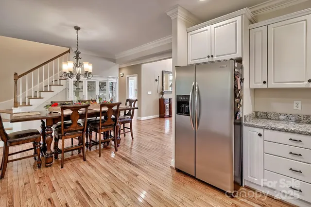 a kitchen with granite countertop a refrigerator a stove a dining table and chairs with wooden floor