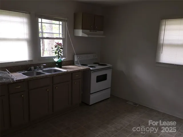 a kitchen with granite countertop a stove a sink and a window