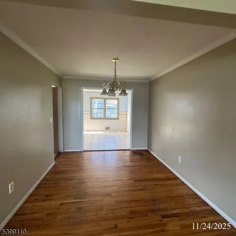an empty room with wooden floor cabinet and windows