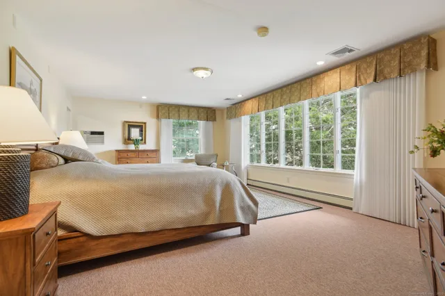 a bed sitting in a spacious bedroom next to a window