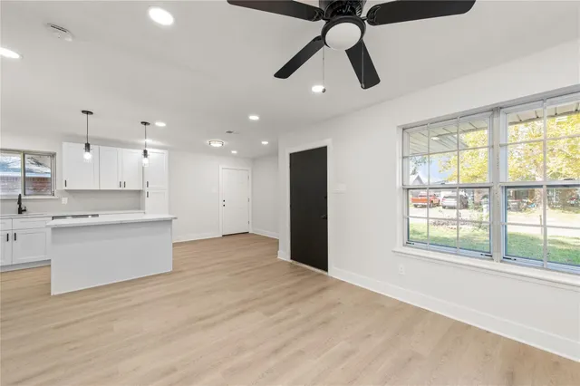 a view of an empty room with window and kitchen view