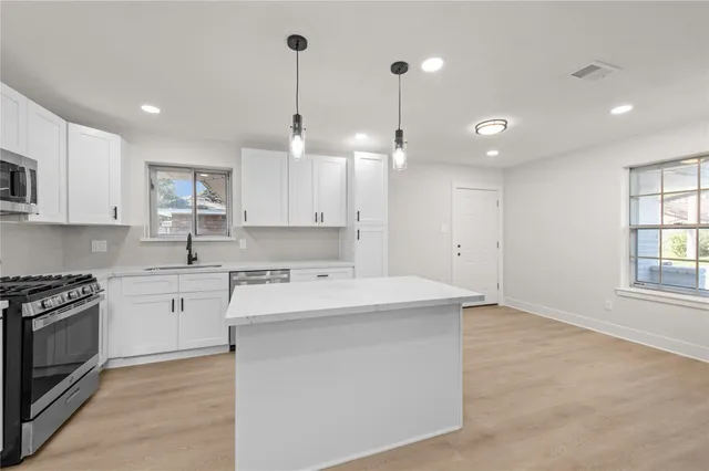 a kitchen that has a sink a stove and cabinets