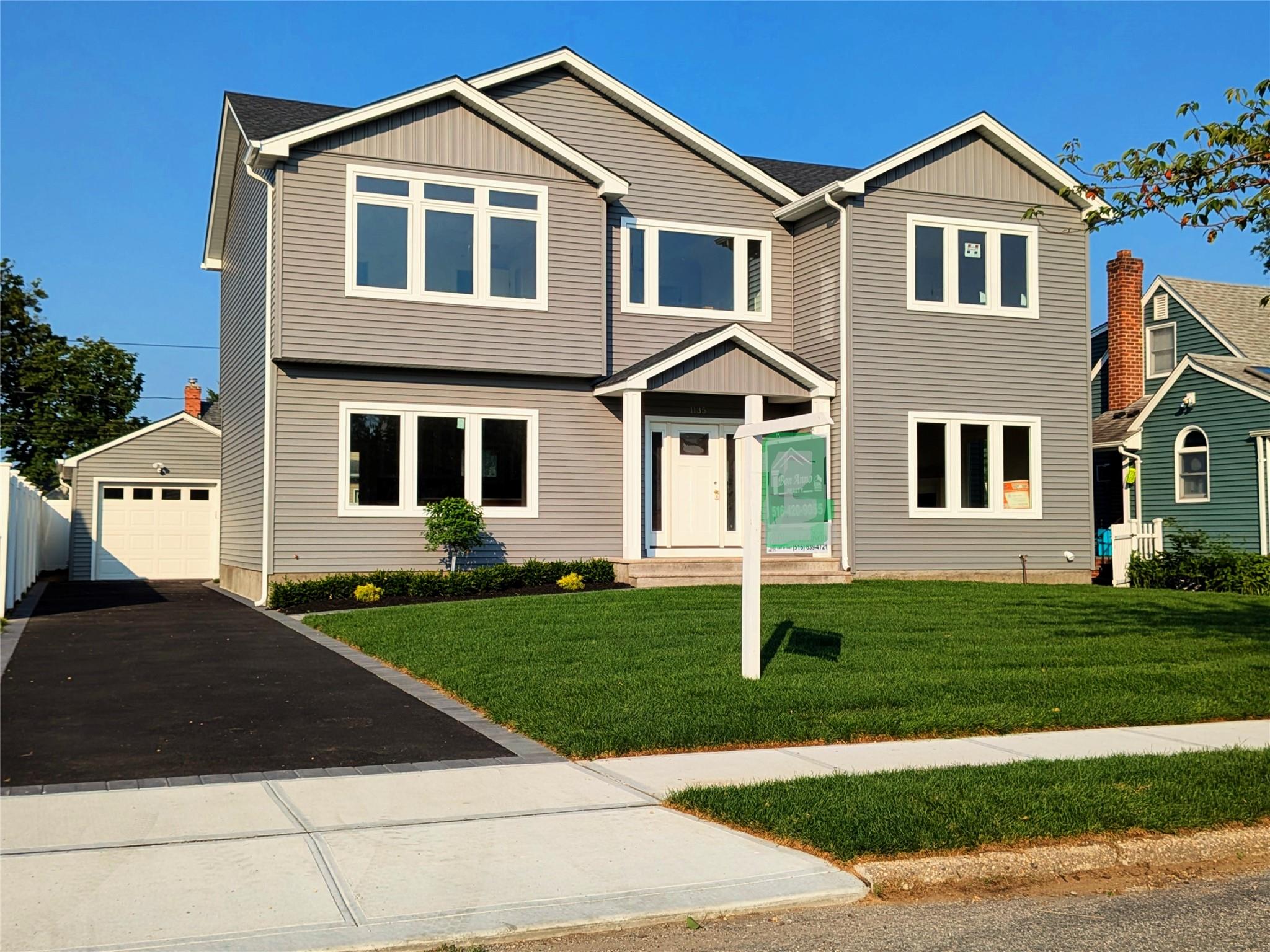 1135 Logan Road Wantagh, NY 11793 - Photo 1 of 1 View of front of house featuring an outbuilding, asphalt driveway, board and batten siding, a detached garage, and a front lawn