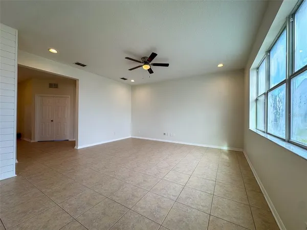 an empty room with ceiling fan and windows